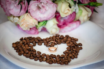 Fototapeta na wymiar Wedding rings on a heart made of coffee beans