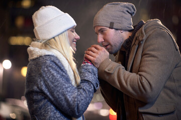 A young couple warming up in a cold night walk in the city. Love, together, walk, snow, city