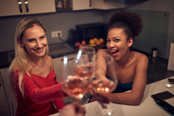 caucasian blonde and afro-american female friend toasting, smiling, looking at camera.