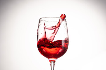 splash of red wine in glass on white background close up