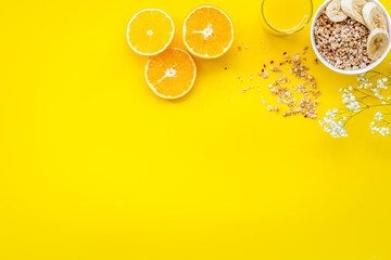 Healthy granola with banana and orange juice for colorful breakfast on yellow background top view mock-up