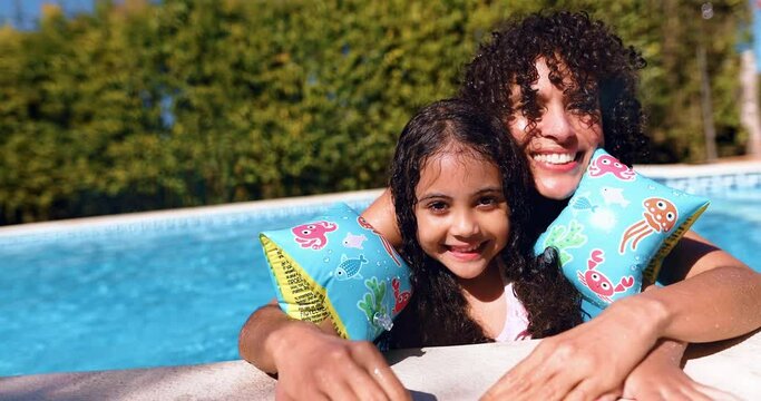 Mother and daughter with floaties in a pool