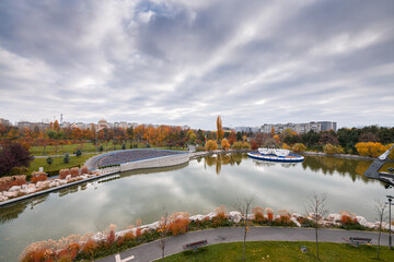 Fototapeta premium Autumn landscape of Drumul Taberei Park in Bucharest city capital of Romania with cloudy sky and great fall colors