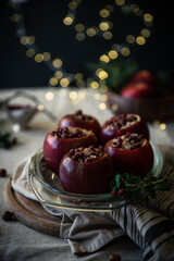 Obraz na płótnie Canvas Preparing Christmas baked apples stuffed with nuts, lingonberry and cinnamon. Glass baking form with apples on festive decorated table..