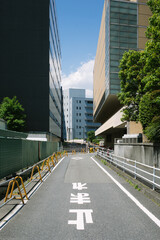 street view of an empty road in tokyo japan during summer with construction and commerical buildings to the side and japanese writing characters on the floor