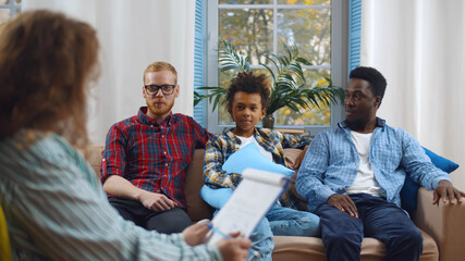 Diverse male gay couple with foster son consulting child protection services worker at home