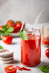 Glass of tomato juice with basil and fresh tomatoes on white background