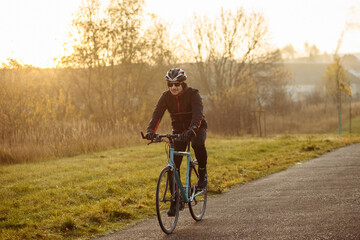 Obraz premium man on a blue bicycle in the morning cold season goes to work