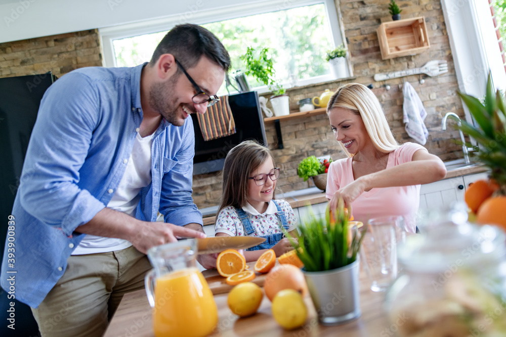 Wall mural Family in the kitchen making orange juice