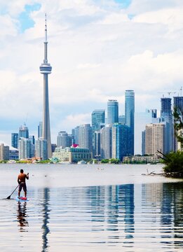 Man Paddleboarding On Lake Against Cityscape