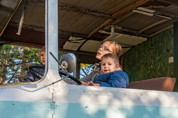 Childrens play in an abandoned bus. A girl drive a bus. The girl turns the steering wheel in the abandoned bus. 