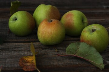 Green apples and autumn leaves on the table