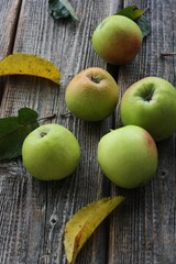 Green apples and autumn leaves on the table
