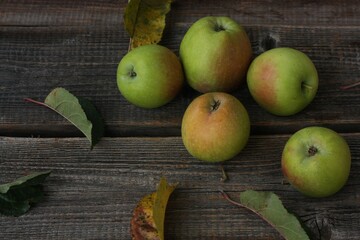 Green apples and autumn leaves on the table