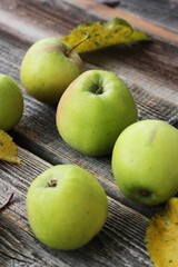 Green apples and autumn leaves on the table
