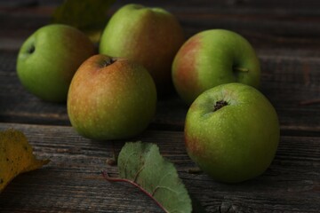 Green apples and autumn leaves on the table