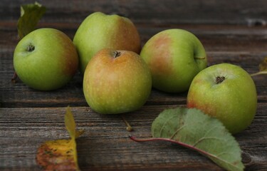 Green apples and autumn leaves on the table