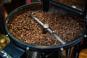 Closeup process of roasting fresh fried coffee beans. Processed coffee beans are mixed around an oven cooling plate