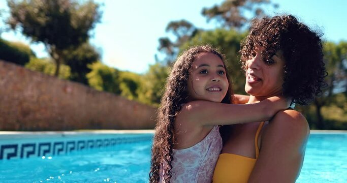 Daughter hugging mother inside a pool playing together