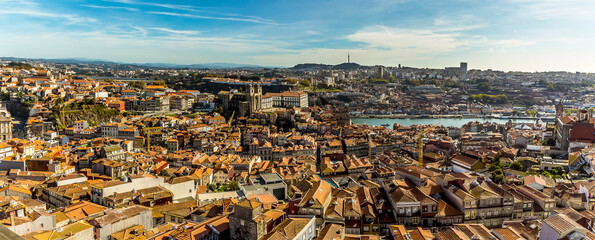 A wide-angle view towards the cathedral and the Douro river across the rooftops of Porto, Portugal from the Clerigos Tower on a sunny afternoon