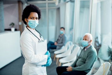 African American female doctor in a hallway at medical clinic during COVID-19 pandemic.