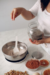 Woman poured spices into a bowl. Confectioner mixes the ingredients. Lady is preparing dessert.