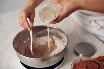Woman pours milk into a bowl. Confectioner mixes the ingredients. Lady is preparing dessert.