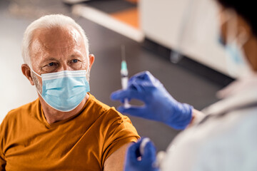 Senior patient getting vaccinated at medical clinic during coronavirus pandemic.