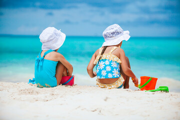 Two little happy girls have a lot of fun at tropical beach playing together