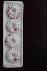 Four white meringue cakes with red pastry crumb sprinkles. Top view