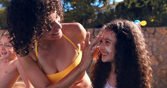Mother applying sunscreen on daughter face in the pool
