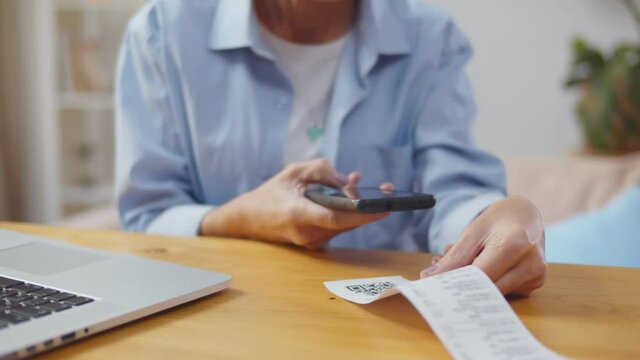 Woman using smartphone and scanning qr code paying bills online