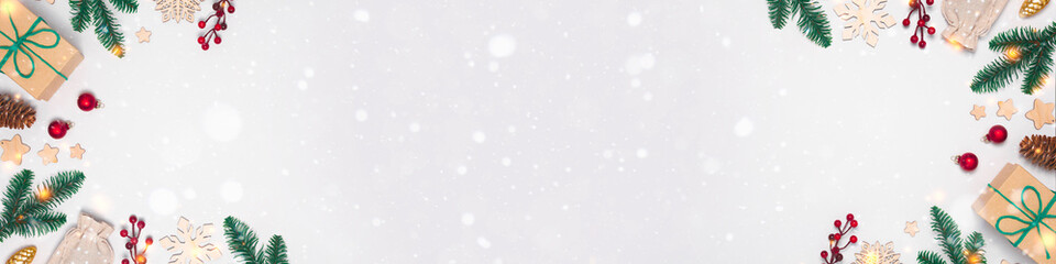 Christmas banner with present in craft paper, baubles, fir tree branches, snow and lights on white background with lights. Flay lay, copy space