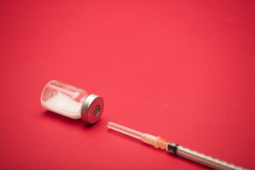 vaccine bottle with syringe, and red background