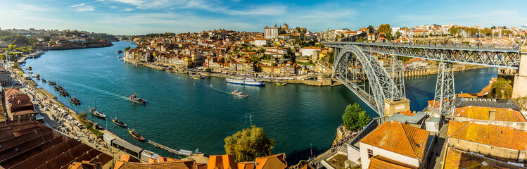Fototapeta premium A panorama of the Douro river, the Dom Luiz bridge and the old quarter of Porto, Portugal on a sunny afternoon