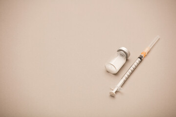 syringe with vaccine bottle, brown background