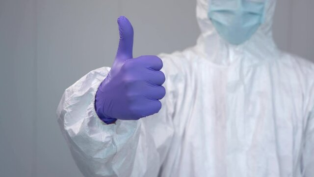 Close up of a nurse in a protective suit gesturing a thumbs up during the coronavirus pandemic, covid 19. Healthcare worker inside a hospital with PPE.