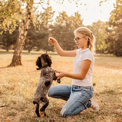 Lifestyle photo of happy young girl with her pet spaniel dog - outdoor in nature
