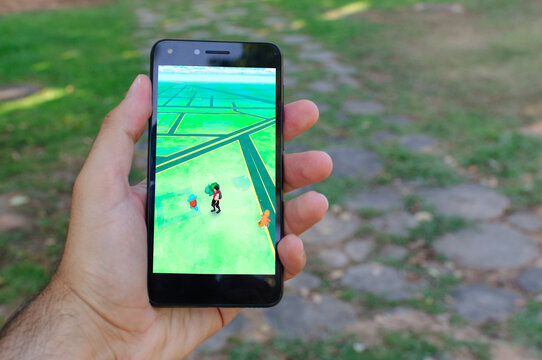 A hand's man plays Pokemon Go with a smartphone at the park.