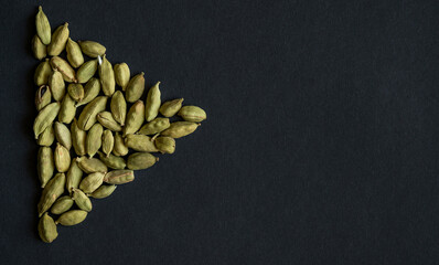 Close up photo of Cardamom pods pile formed as PLAY sign icon on the matt black background. Cardamom is very popular in Indian and Sri Lanka cuisine.