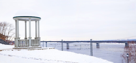 Rotunda on the river bank against the background of the bridge. Horizontally.