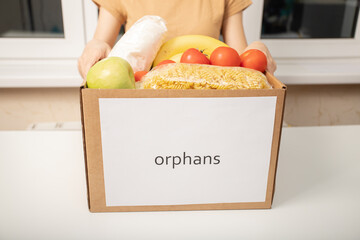 A young woman volunteer with a box of food products for orphans in orphanages