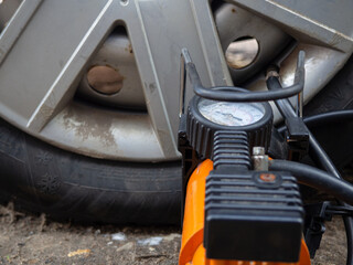 puncture of a tire on the road. compressor pumping of auto wheels on the road. electric pump for wheels.