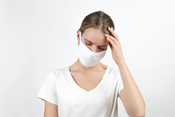 Young blond woman in virus disposable face mask  keeping raised hand on her head expressing feelings, sadness, worried. Protection for covid-19