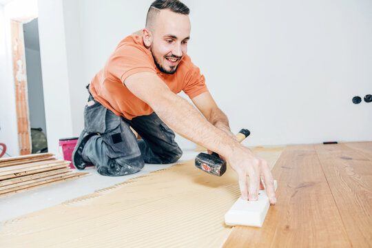 A Male Worker install wood floor on a house