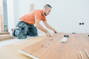 A Male Worker install wood floor on a house - 393925846
