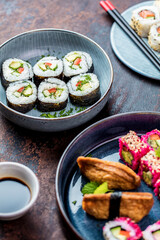 Delicious rolls, sushi and maki on a dark wooden Board with chopsticks. On black rustic background