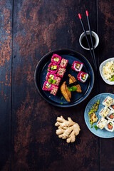 Delicious rolls, sushi and maki on a dark wooden Board with chopsticks. On black rustic background
