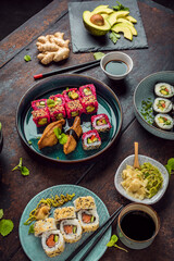 Delicious rolls, sushi and maki on a dark wooden Board with chopsticks. On black rustic background
