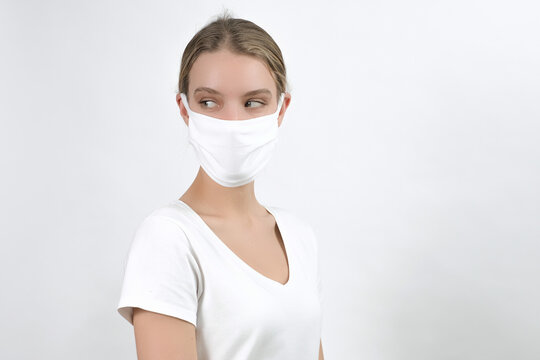 young caucasian blonde woman in disposable face protection mask points aside on free space, indoor studio photo on the white background, advertising